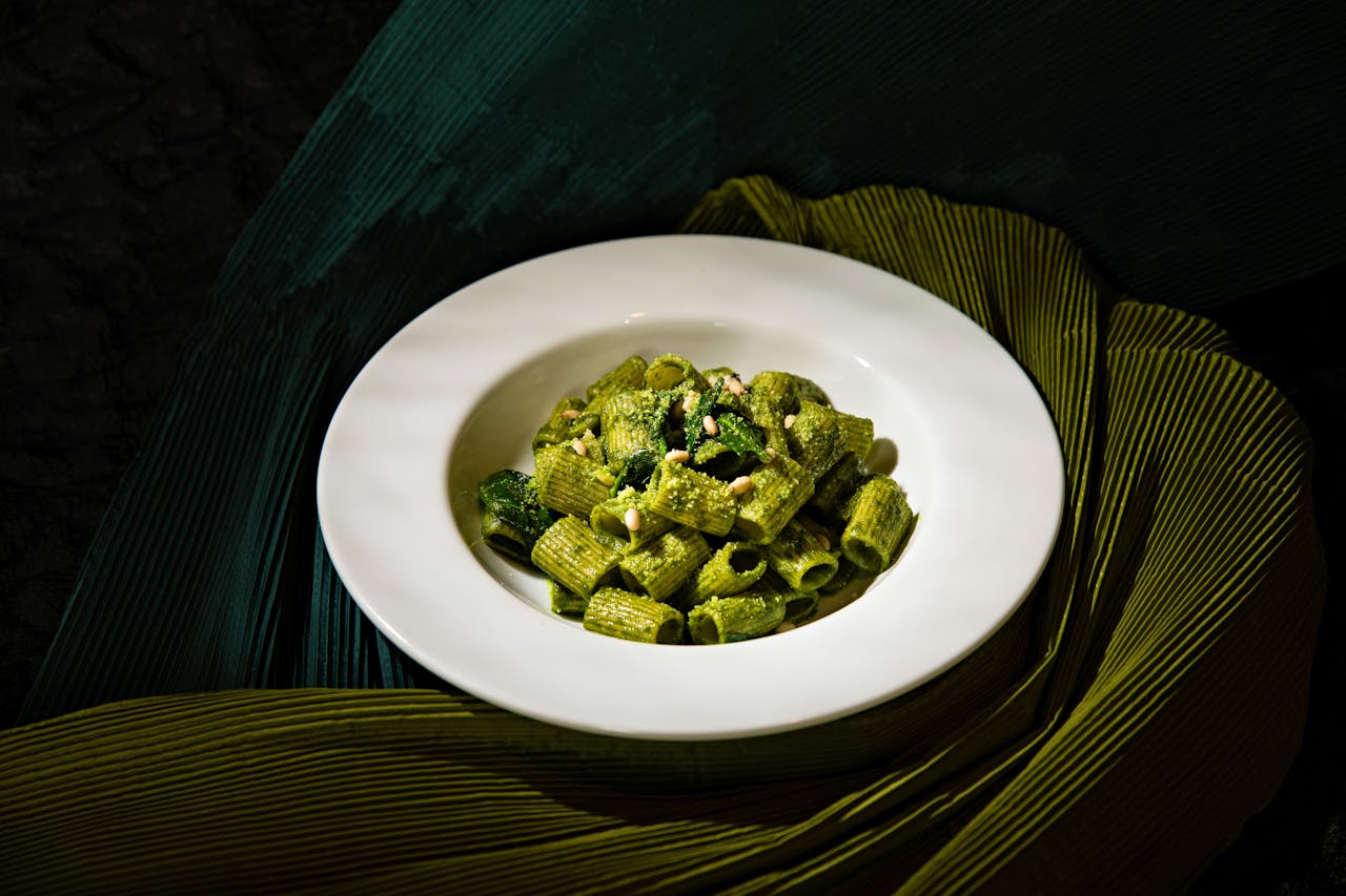A plate of delicious rigatoni pasta with fresh spinach pesto arranged artfully.